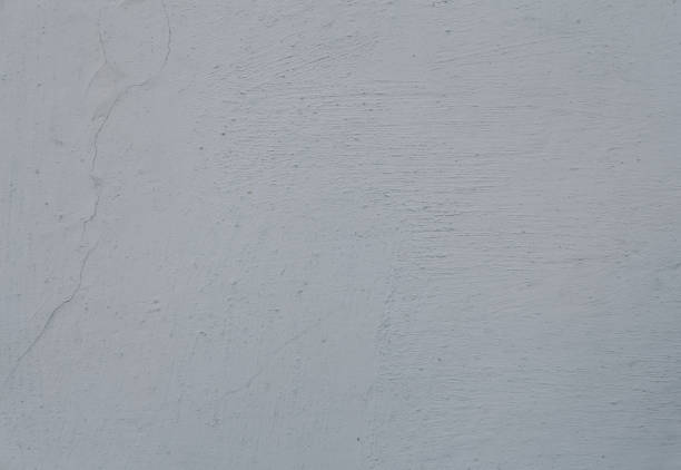 istock An old cement painted wall, white grey abstract background. A scratched concrete wall texture with cracks. 1405759817