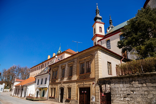 Litomysl, Czech Republic, 17 April 2022:  narrow picturesque street with medieval colorful gothic merchant houses at sunny summer day, historic renaissance and baroque buildings, medieval church