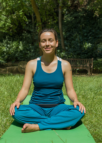 full length photo of a woman smiling at camera while is sitting on a mat with hands on knees
