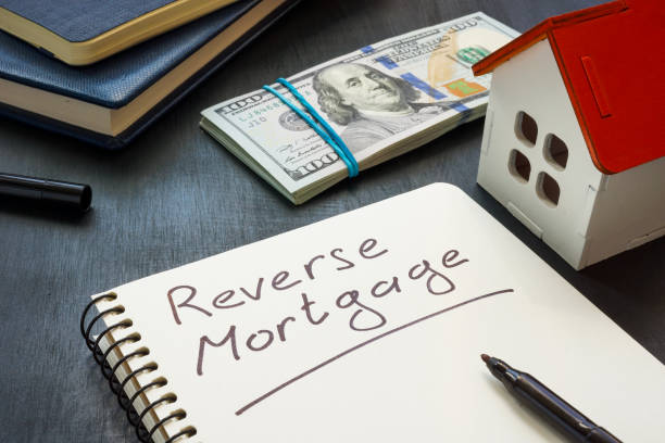 istock Notepad with the inscription Reverse mortgage, house model and money. 1405762855