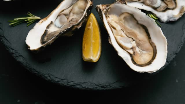 Oysters with lemon on black plate