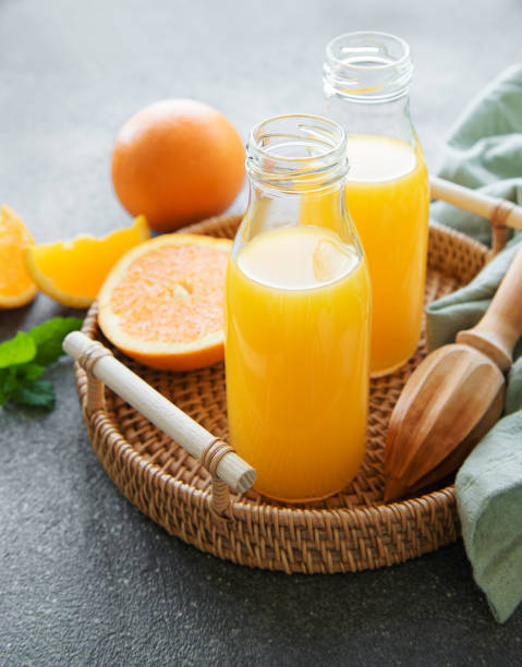 бутылки свежего апельсинового сока - freshly squeezed стоковые фото и изображения