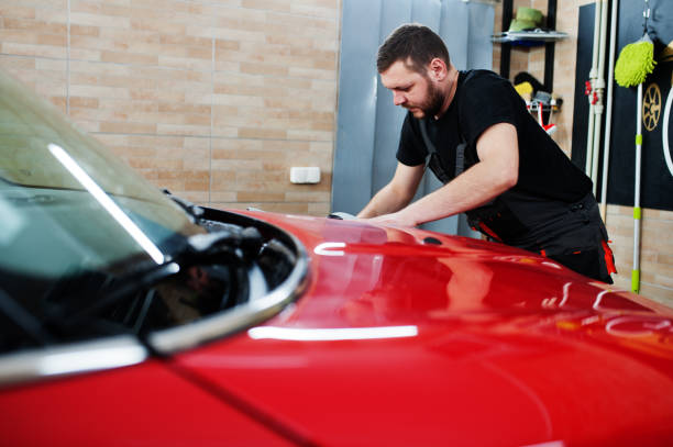 istock Man worker washing red car in detailing garage. 1405765440