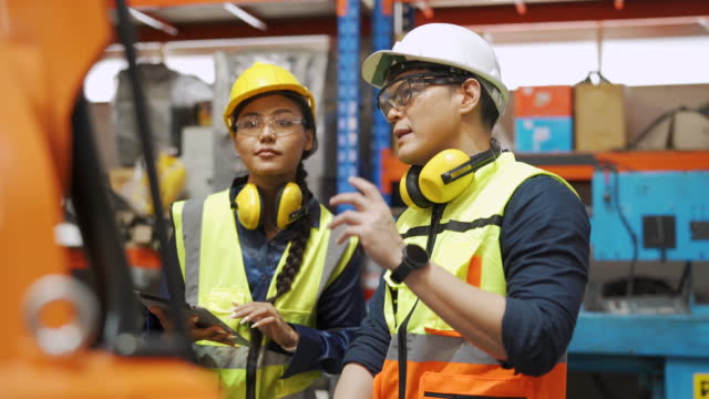 Asian engineers working with robot machinery
