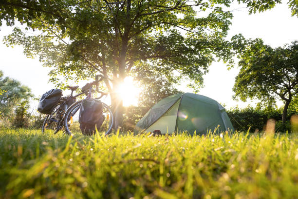 Bicycle with panniers next to a tent at sunset stock photo