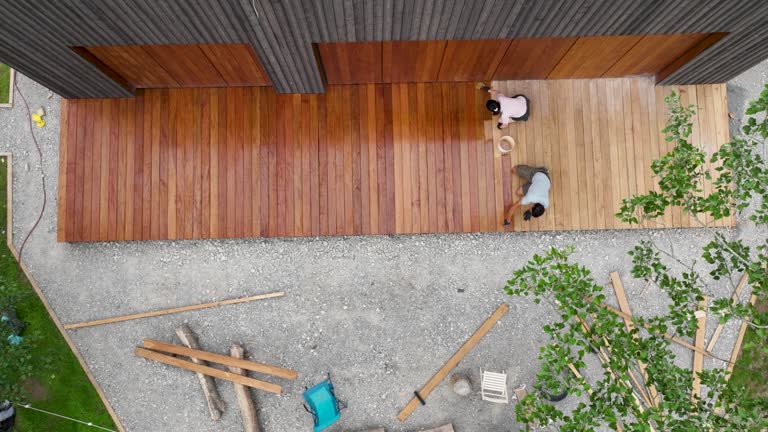 Painting wooden decking in front of a cabin house