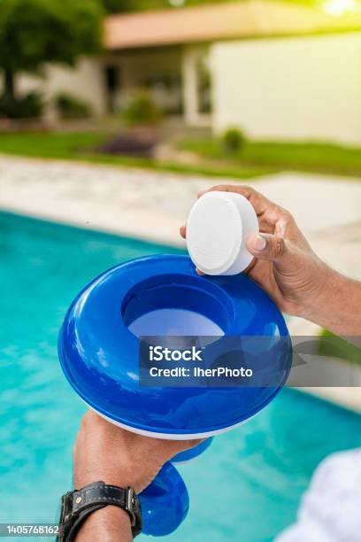 Hand Of A Pool Disinfection Worker Holding A Dispenser With A Chlorine Tablet Hands Holding A Dispenser With Pool Chlorine Tablet Pool Float And Chlorine Tablets For Pool Maintenance Hands Holding A Pool Chlorine Dispenser Stock Photo - Download Image Now