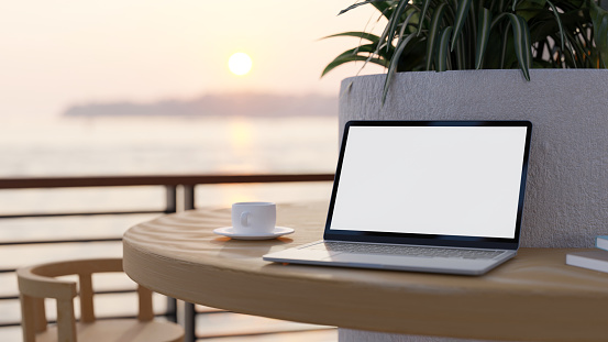 Beautiful outdoor workspace or restaurant cafe exterior design with a portable notebook laptop white screen mockup and coffee cup on the table with beautiful sea view. 3d rendering, 3d illustration
