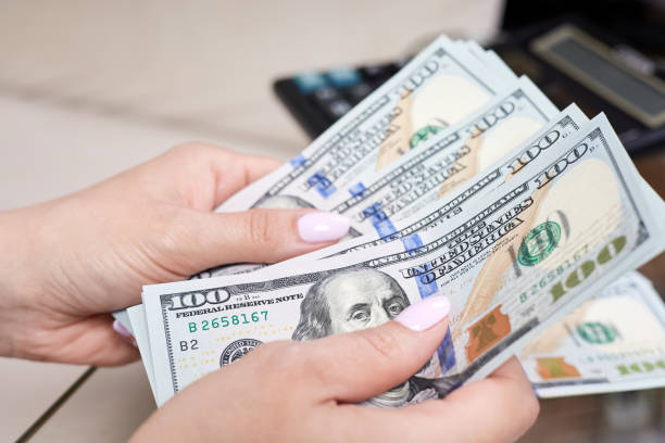 una ragazza conta banconote da 100 dollari su un tavolo di vetro - money making foto e immagini stock