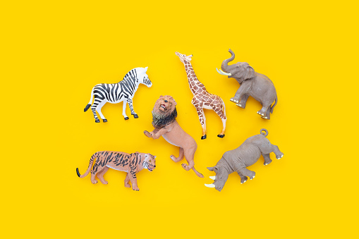 Plastic jungle animal toys on yellow background.