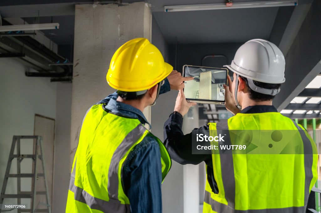 Engineer, architect and construction supervisor Use tablet to record information while inspecting construction work. Construction supervisor, architect or engineer inspect construction inside building Building Information Modeling Stock Photo