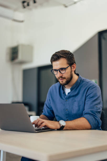 istock Serious-looking male working online, typing something on the laptop keyboard. 1405776575