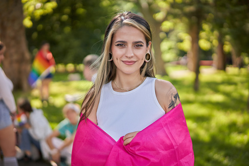 A bisexual woman holding a bisexuality flag with his arms outstretched during gay pride event