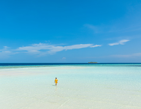 Beautiful woman walking in transparent turquoise sea