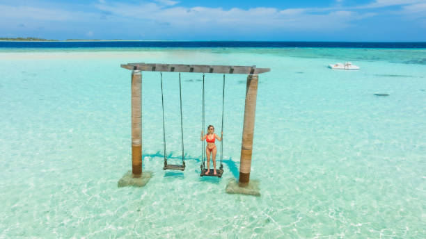 Beautiful woman enjoying swing in ocean on her vacation stock photo
