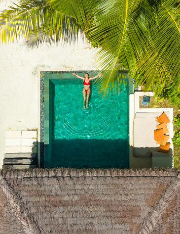Hermosa mujer disfrutando de la piscina bajo la palmera photo