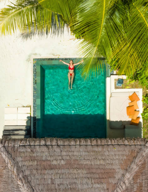 istock Beautiful woman enjoying pool under palm tree 1405779473