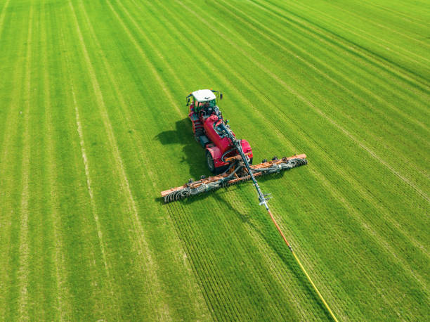 Tractor injecting livestock liquid manure with in a field Tractor injecting livestock liquid manure with in a field seen from above during springtime using a drag hose injector to minimalize the  compaction of the soil during fertilisation. ammonia fertilizer stock pictures, royalty-free photos & images