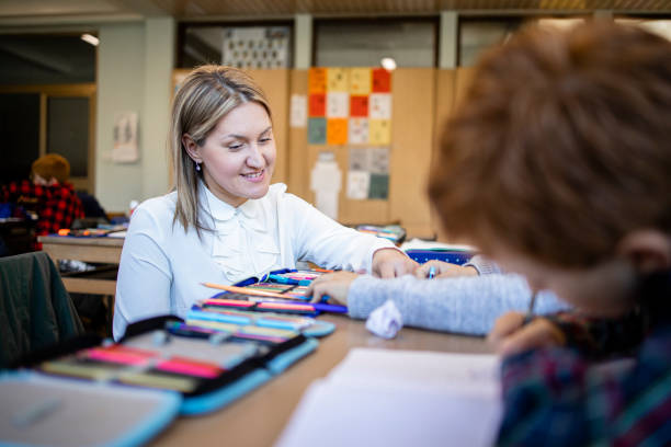 istock School teacher and students working together on their schoolwork in classroom. 1405779896