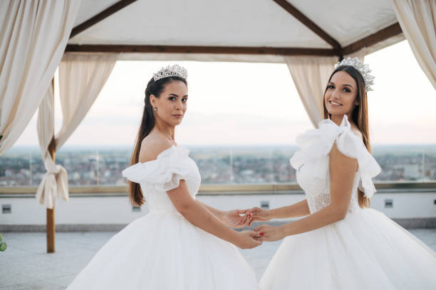 Two beautiful brides posing in sunset on terrace. Wedding dresses, friends and gorgeus decoration.