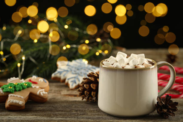istock Delicious hot chocolate with marshmallows and Christmas decor on wooden table against blurred lights, space for text 1405787621