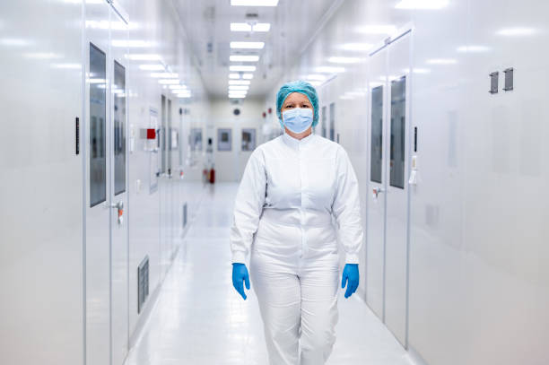 Woman in safety workwear seen in a hallway of drug manufacturing laboratory in pharmaceutical industry stock photo