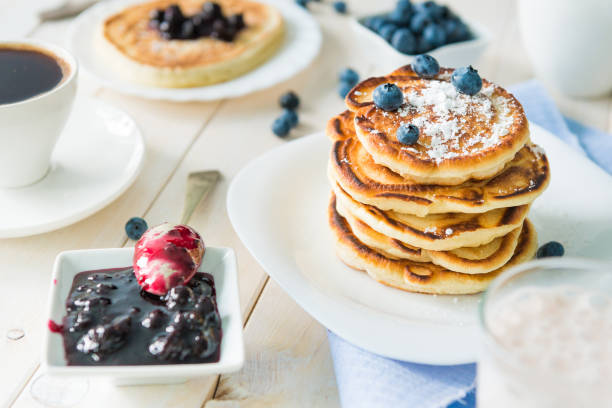 pancakes with blueberry and jam on white wooden table