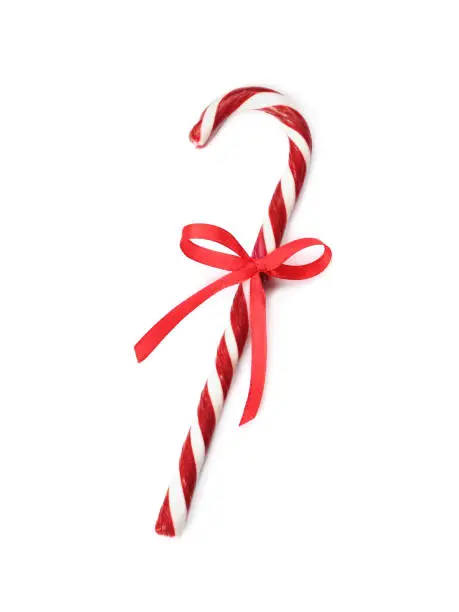 Delicious Christmas candy cane with red bow isolated on white, top view