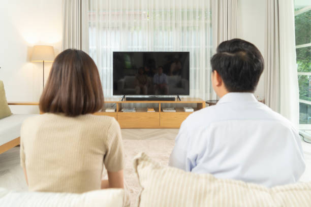 feliz pareja viendo una película en la pantalla en blanco de la televisión en la sala de estar en la sala de cine en casa en una casa. estilo de vida de las personas. - apartment television family couple fotografías e imágenes de stock