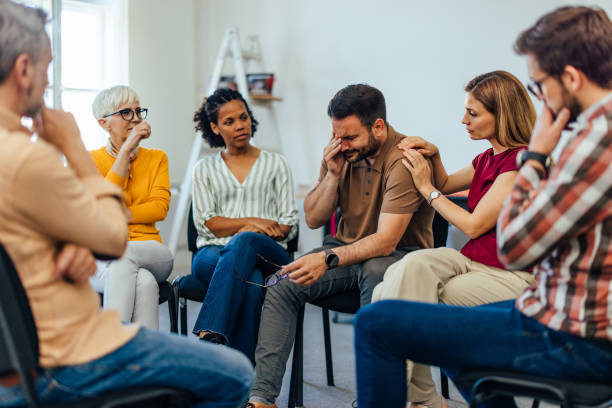 istock Man holding his tears back, at the group therapy while having support from people around him. 1405791484