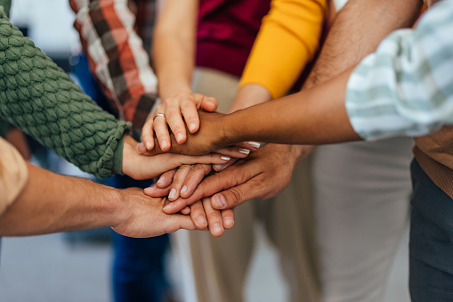 People holding hands in the middle, one over the others.