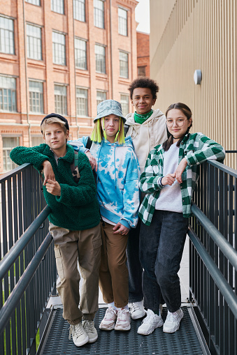 Portrait of group of trendy multiethnic teenagers looking at camera while hanging out after school