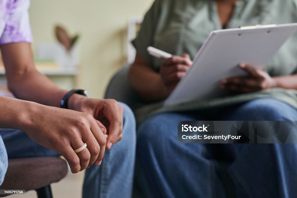 Teenager talking to psychologist at session Close-up of African teenage boy sitting at psychotherapy and talking to specialist Mental Health Professional Stock Photo