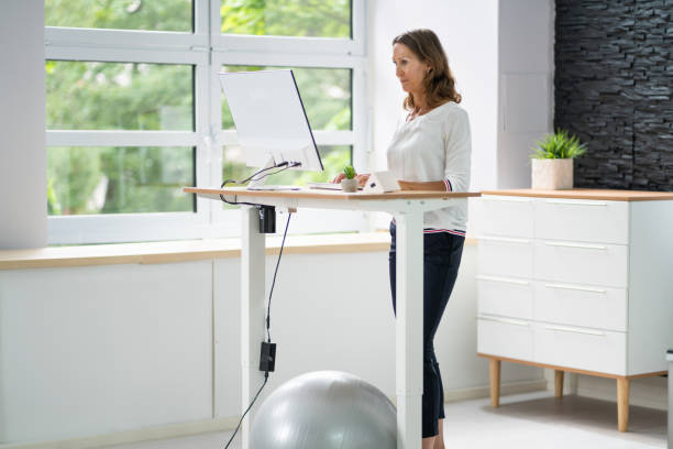 istock Woman Using Adjustable Height Standing Desk In Office 1405791796