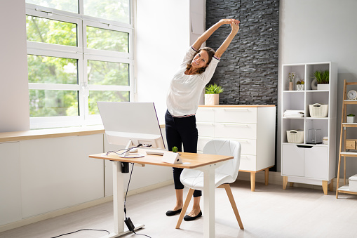 Young Businesswoman Stretching Her Arms At Desk
