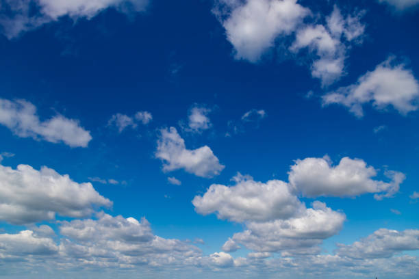 istock White cumulus clouds on a clear blue sky. 1405792660