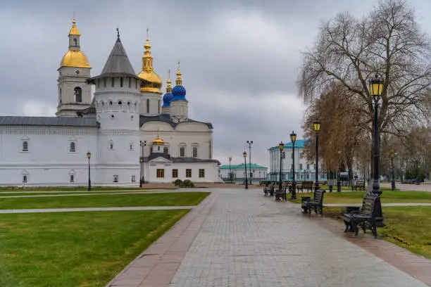 White-stone Kremlin in historical city of Tobolsk (Siberia, Russia) in autumn. Ancient churches, cathedrals with golden domes and towers. Benches, lanterns, tall trees and green lawns create comfort