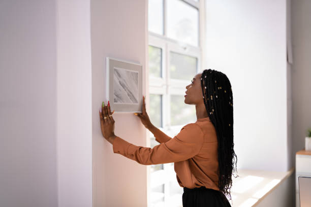 istock Woman Putting Photo Frame On Wall 1405793060