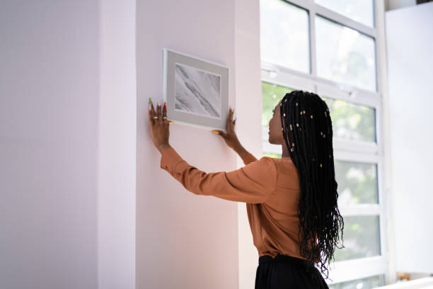 istock Woman Putting Photo Frame On Wall 1405793080