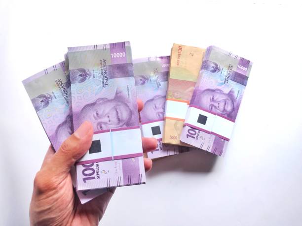 istock Hand holding and Showing a bundle of 10.000 Indonesian Rupiah 1405793672