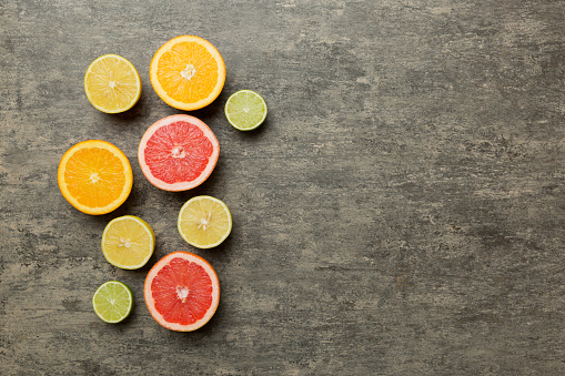 Fruit background. Colorful fresh fruits on colored table. Orange, lemon, grapefruit Space for text healthy concept. Flat lay, top view, copy space.