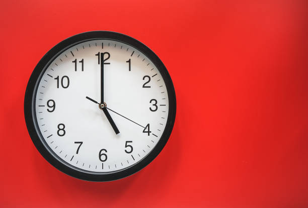 istock Classic black and white analog clock on red background at Five o'clock with copy space 1405796505