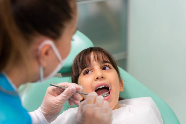 dentista no consultório do dentista examinando os dentes da menina - dentists chair dentist office chair orthodontist - fotografias e filmes do acervo