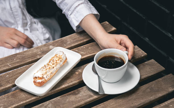 istock Cup of coffee and eclair on a wooden table close-up. 1405799210