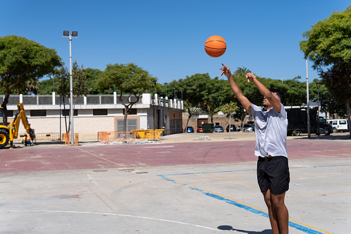 Young muslim boy playing basketball in the street, ball throwing, training concept and sport