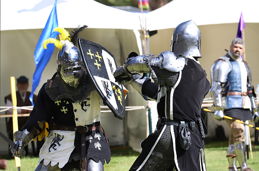 Gumeracha , South Australia, Australia - May 2021: Gumeracha Medieval Fair, local community event. Knights in metal helmets and armour with swards fight, a part of a costume performance at a medieval fair, reconstruction of knightly battles.