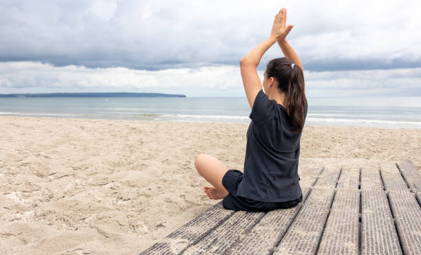 istock A woman meditates while sitting on the seashore. 1405803125