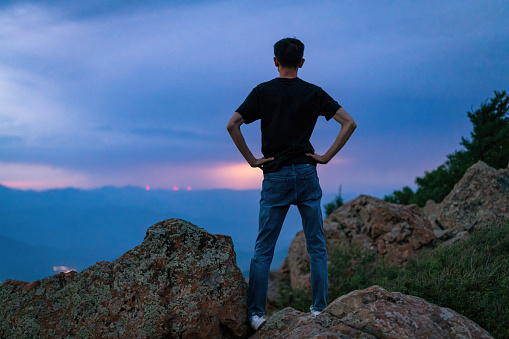 A man was on the top of the mountain observing lightning and extreme weather