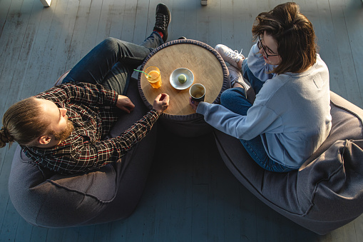A young woman and man talking while sitting on bean bags, top view, dating, friendship concept.