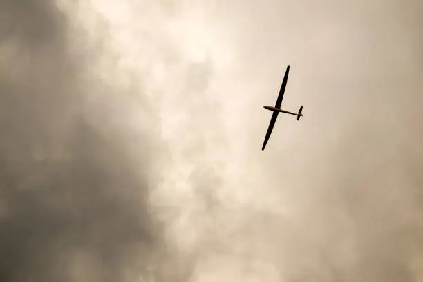 Sky sights, sailplane flying among storm clouds in gray sky